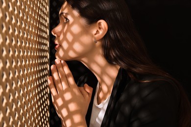 Woman praying to God during confession in booth