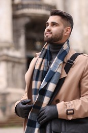 Smiling man in warm scarf on city street