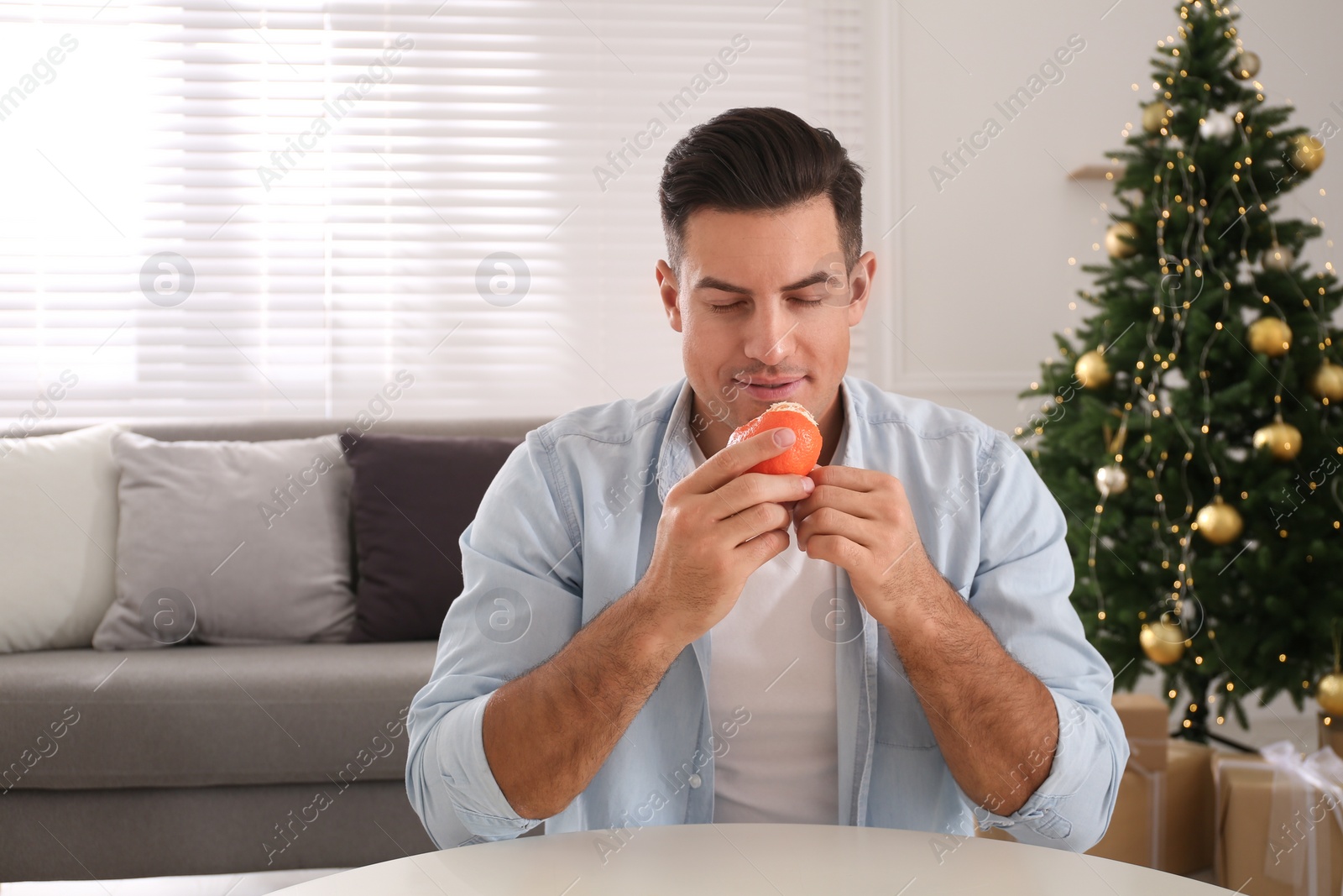 Photo of Happy man with fresh tangerine at table in room