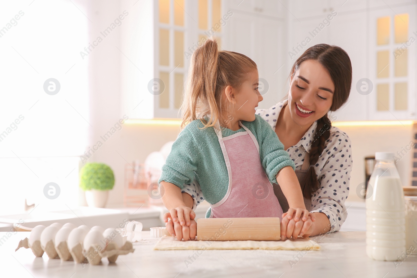 Photo of Mother and daughter rolling out dough in kitchen at home