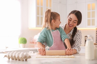 Mother and daughter rolling out dough in kitchen at home