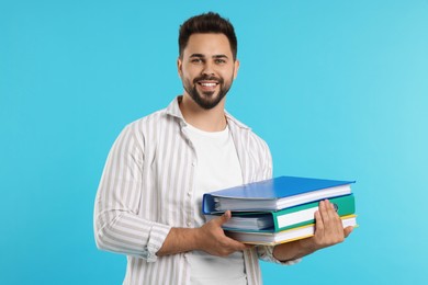 Photo of Happy man with folders on light blue background
