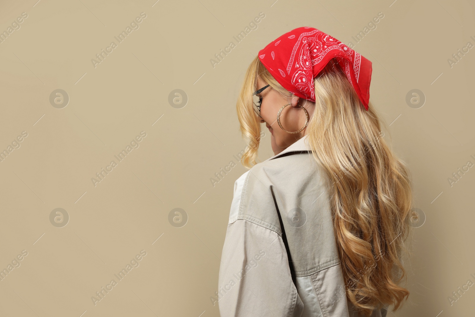 Photo of Young woman with stylish bandana on beige background. Space for text