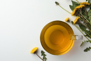 Delicious fresh tea and beautiful dandelion flowers on white background, flat lay. Space for text