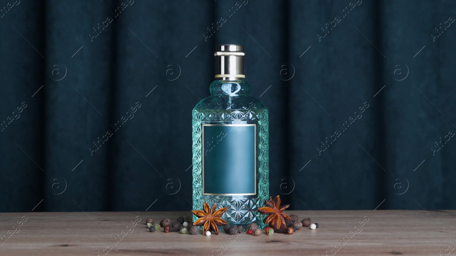 Photo of Bottle of perfume and different spices on wooden table