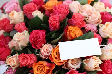 Photo of Bouquet of beautiful roses with blank card, closeup