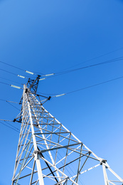 Photo of Modern high voltage tower against blue sky, low angle view