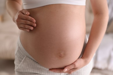 Photo of Young pregnant woman on blurred background, closeup view