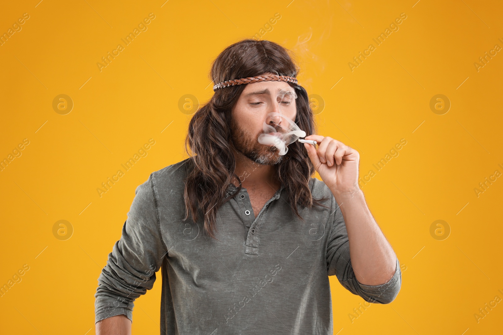 Photo of Hippie man smoking cigarette on orange background