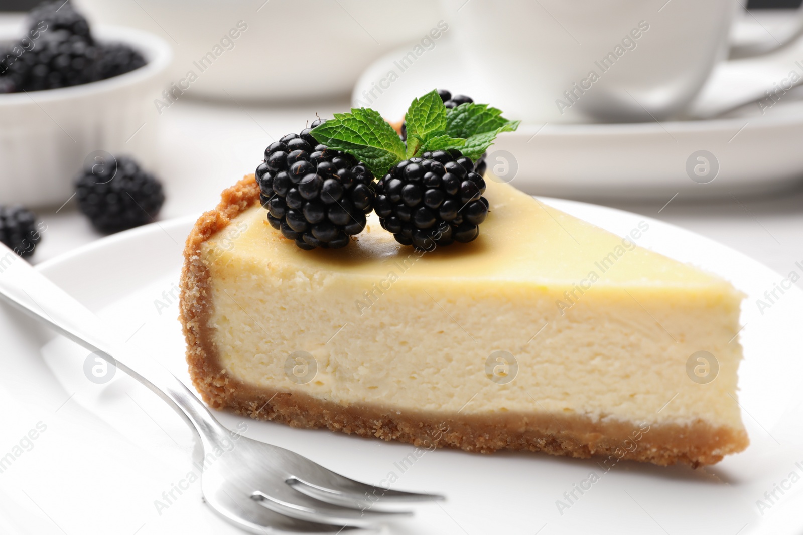 Photo of Piece of delicious cheesecake decorated with blackberries on table