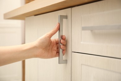 Photo of Woman opening cabinet door at home, closeup