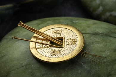 Photo of Acupuncture needles and ancient coin on stone, closeup