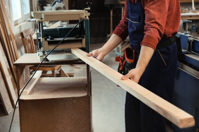 Photo of Working man using thickness planer at carpentry shop, closeup