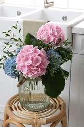 Photo of Beautiful hortensia flowers in vase on stand indoors