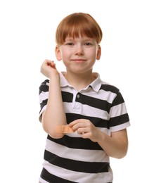 Little boy putting sticking plaster onto elbow on white background