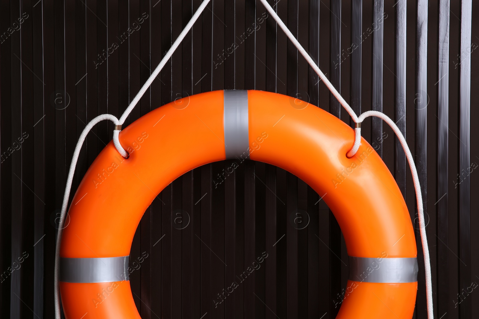 Photo of Orange lifebuoy on dark wooden background. Rescue equipment