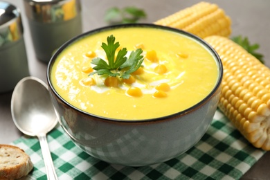 Delicious creamy corn soup served on table, closeup