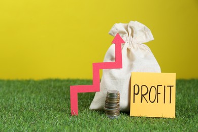 Photo of Sticky note with word Profit, coins, bag, up arrow against yellow background, space for text