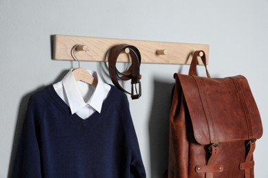 Shirt, jumper and bag hanging on white wall. School uniform