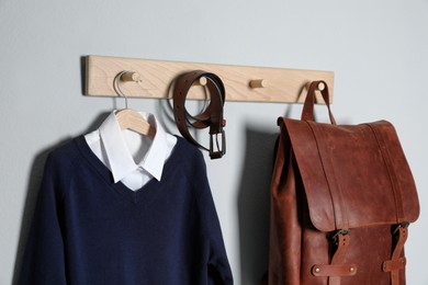 Photo of Shirt, jumper and bag hanging on white wall. School uniform