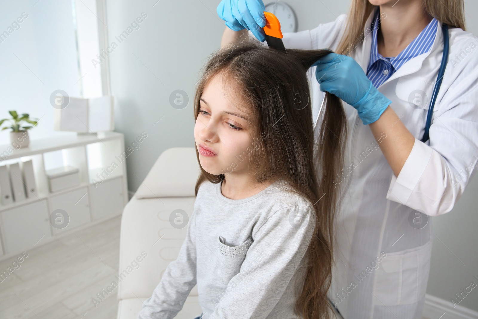 Photo of Doctor using nit comb on girl's hair in clinic. Anti lice treatment