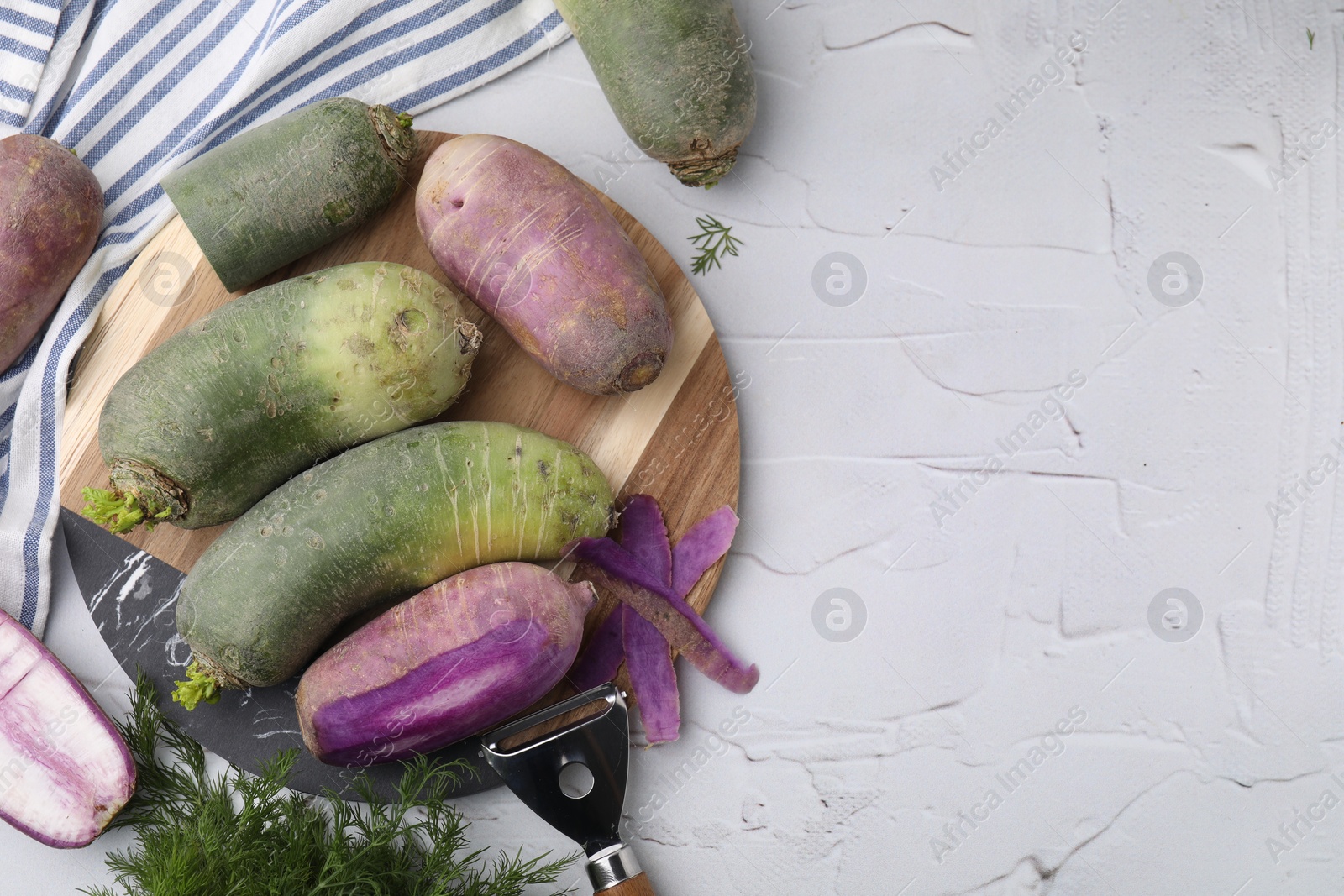 Photo of Daikon radishes, dill and peeler on white textured table, flat lay. Space for text