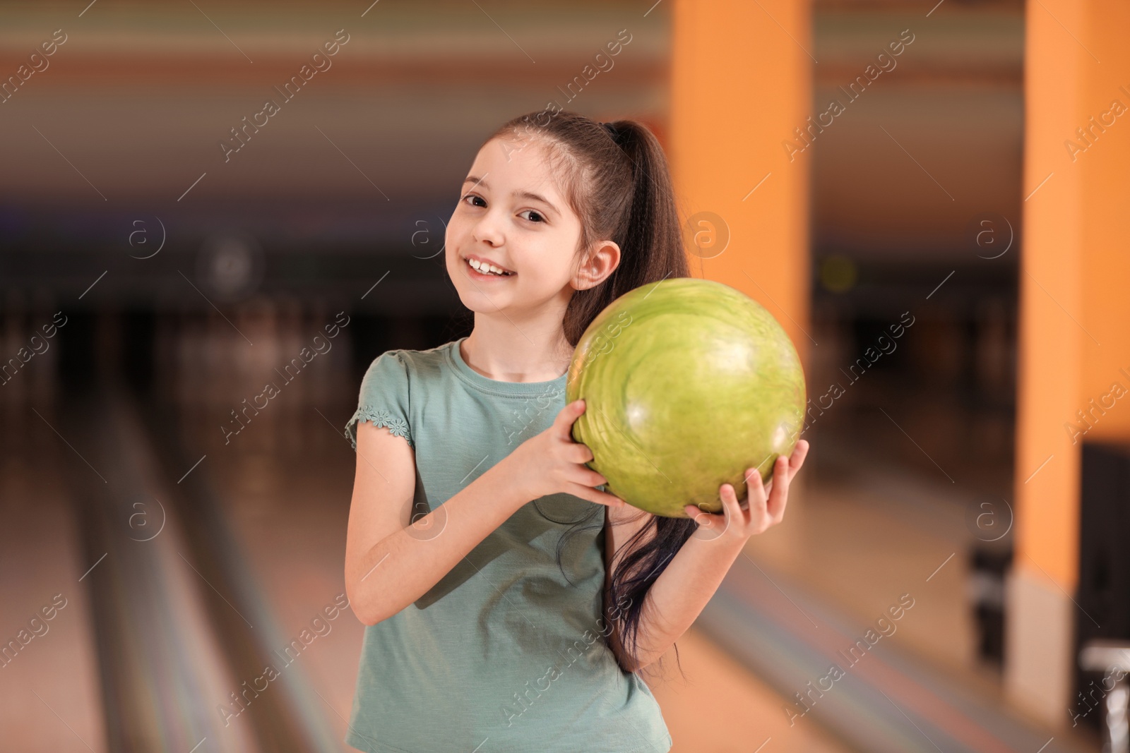 Photo of Little girl with ball in bowling club