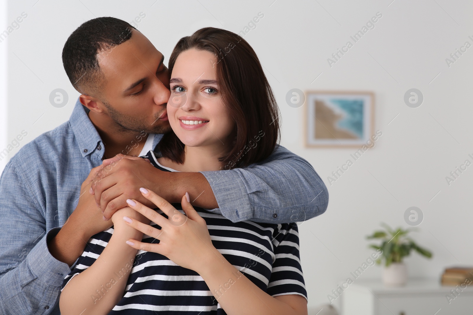 Photo of Dating agency. Man hugging his girlfriend indoors, space for text