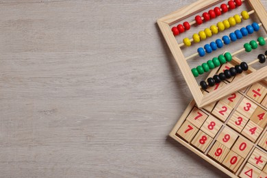 Photo of Math game with numbers and colorful toy abacus on white wooden table, flat lay. Space for text