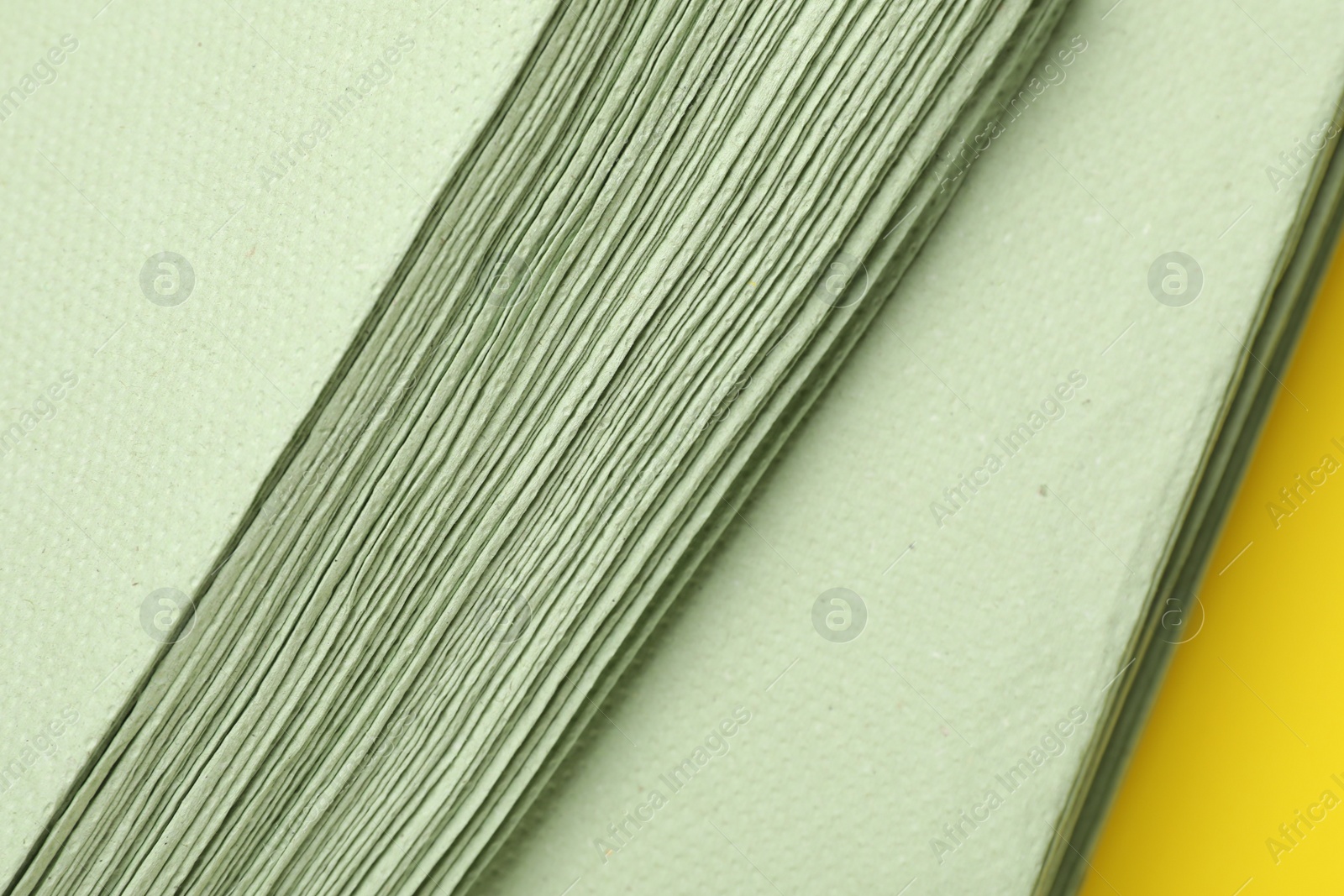 Photo of Green paper towels on yellow background, closeup