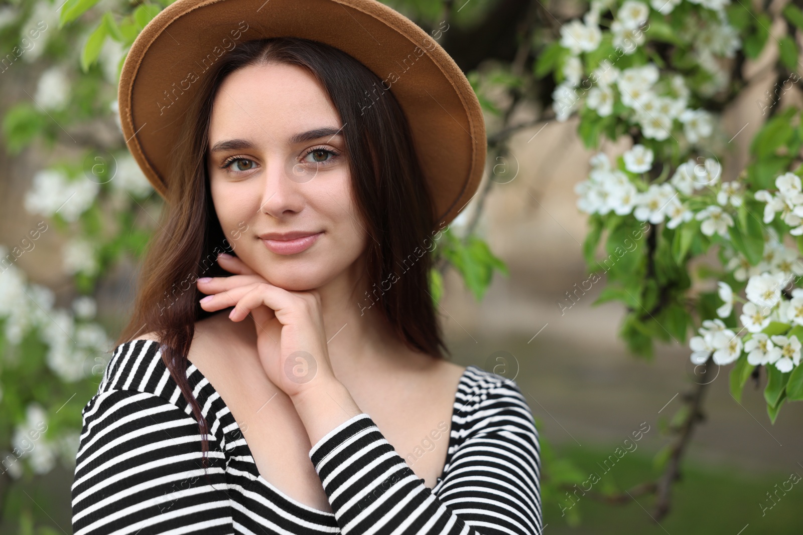 Photo of Beautiful woman in hat near blossoming tree on spring day