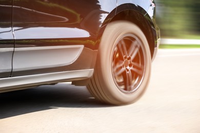 Image of Black car driving on road outdoors, closeup with motion blur effect