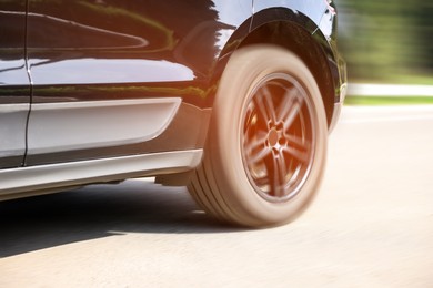 Black car driving on road outdoors, closeup with motion blur effect