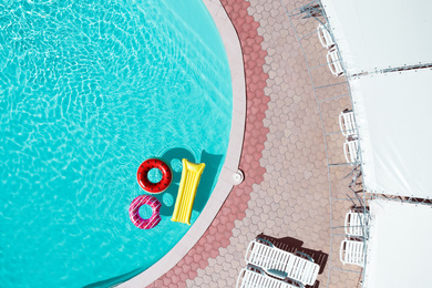 Image of Inflatable rings and mattress floating in swimming pool, top view. Summer vacation