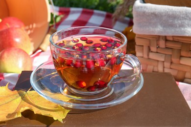 Cup of tea with hawthorn berries outdoors, closeup