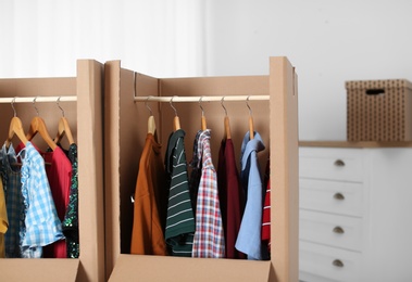 Photo of Wardrobe boxes with clothes on hangers indoors