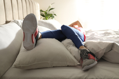 Photo of Lazy young woman sleeping on bed instead of morning training, focus on legs