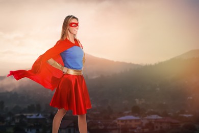 Superhero, motivation and power. Woman in cape and mask on high top in mountains