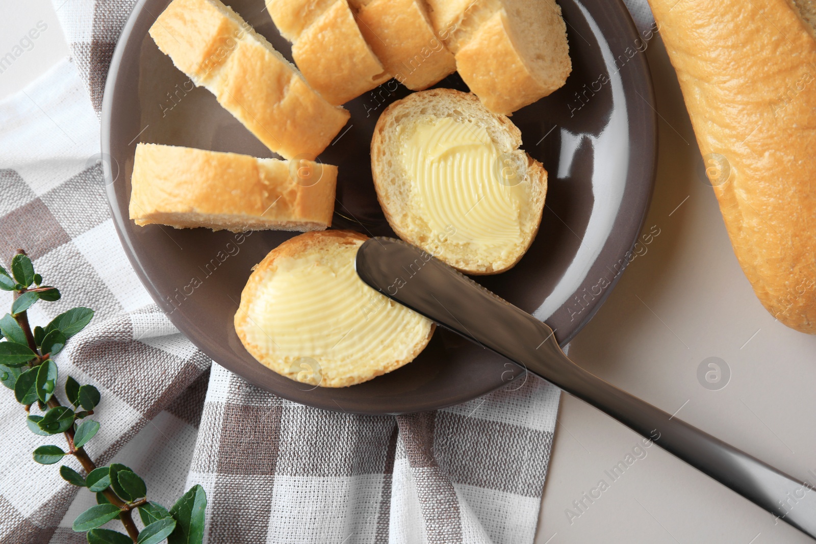 Photo of Whole and cut baguettes with fresh butter on table, flat lay