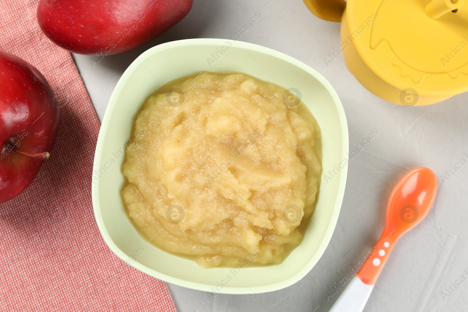 Photo of Healthy baby food. Bowl with delicious apple puree on light grey table, flat lay