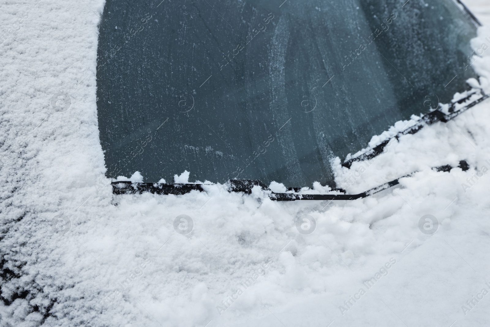 Photo of Car windshield with wiper blades cleaned from snow outdoors on winter day