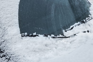 Photo of Car windshield with wiper blades cleaned from snow outdoors on winter day