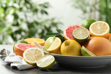 Photo of Different fresh citrus fruits on grey table against blurred background, closeup