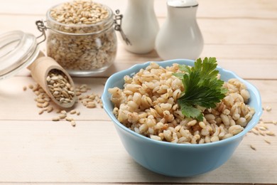 Photo of Delicious pearl barley with parsley on wooden table, closeup. Space for text