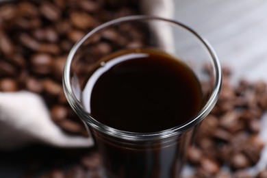 Photo of Shot glass of coffee liqueur on blurred background, closeup