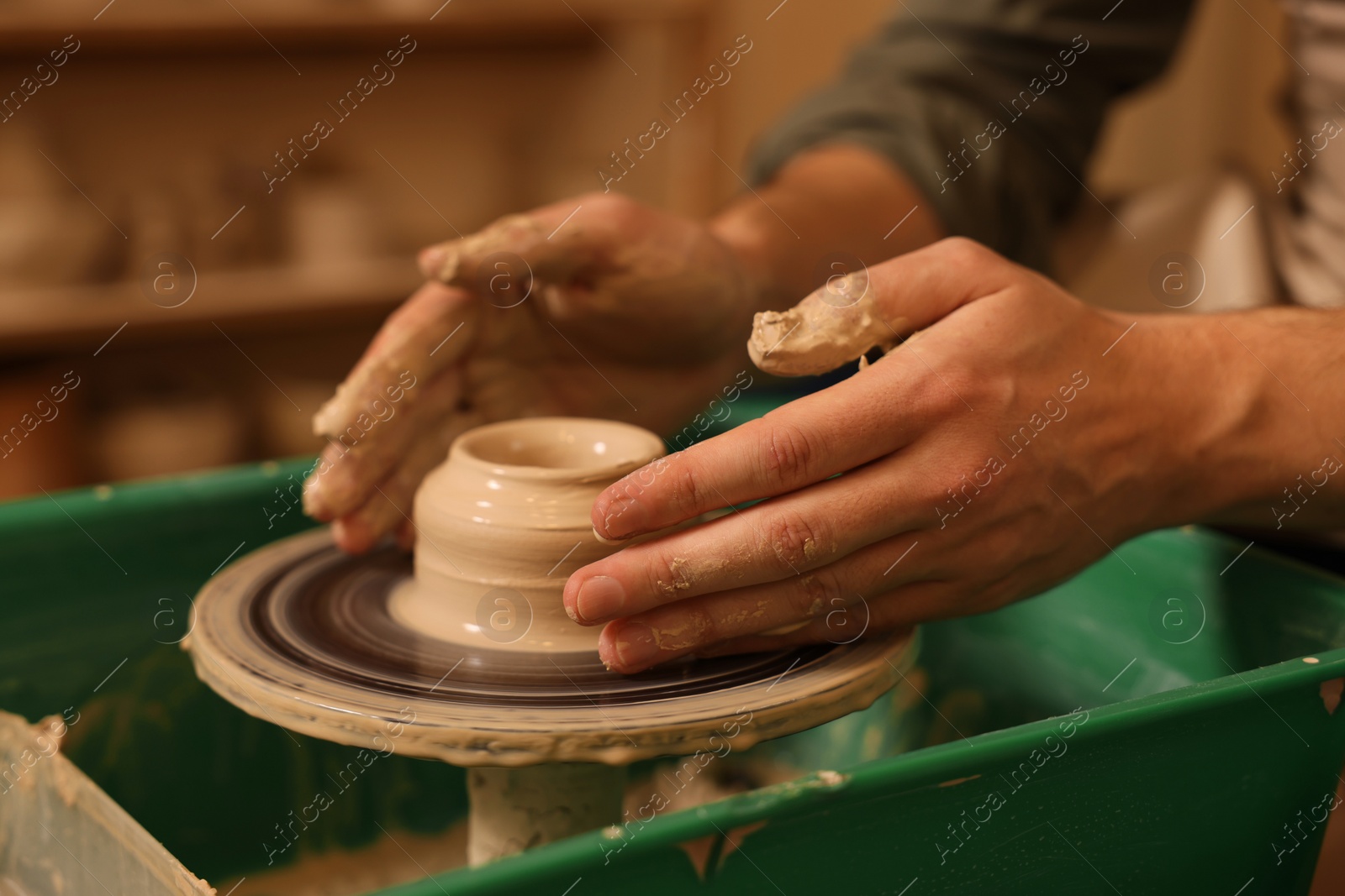 Photo of Clay crafting. Man making bowl on potter's wheel indoors, closeup