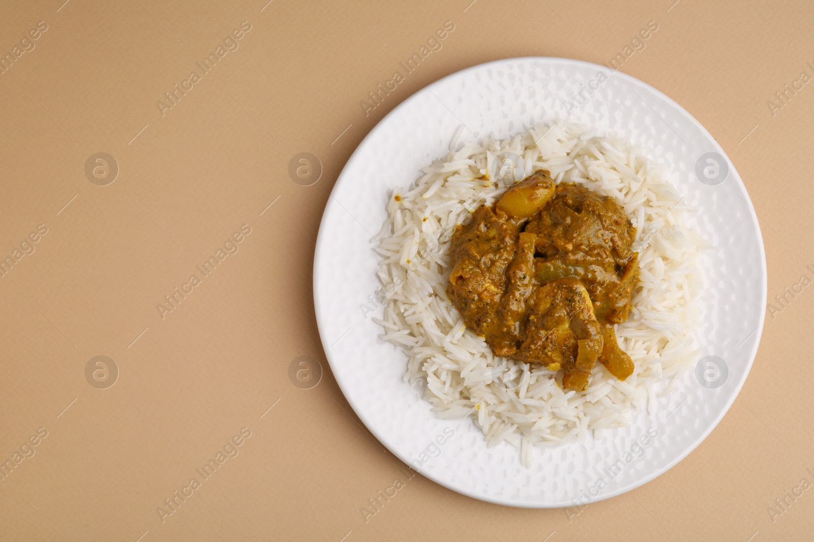 Photo of Delicious chicken curry with rice on beige background, top view. Space for text