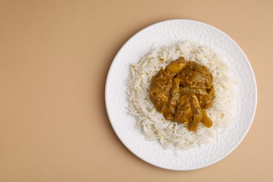 Photo of Delicious chicken curry with rice on beige background, top view. Space for text