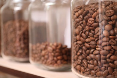 Photo of Glass jars with coffee beans on rack, closeup. Space for text
