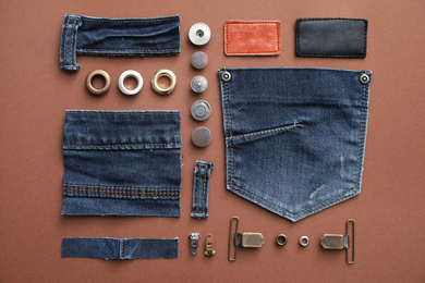 Photo of Flat lay composition with garment accessories and cutting details for jeans on brown background